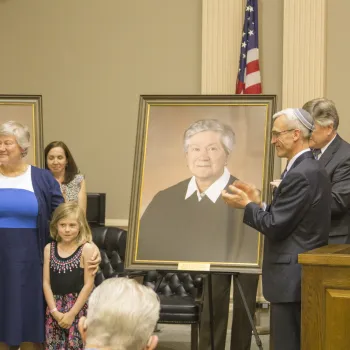 Retired Judge Holly B. Fitzsimmons and her granddaughter stand beside her portrait presented by Alyssa Esposito, a former law clerk for Judge Fitzsimmons, and James Ross Smart Esq. and Patrick A. Klingman Esq., Co-Chairs of the Federal Practice Section at