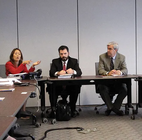 Image of two men and a woman at a table discussion