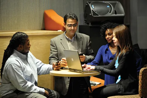 Image of men and women looking at a laptop screen.