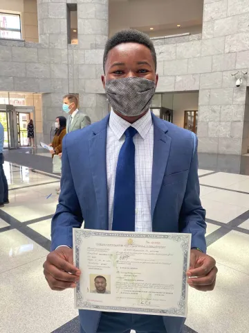 A happy new American displays his certificate of U.S. citizenship.