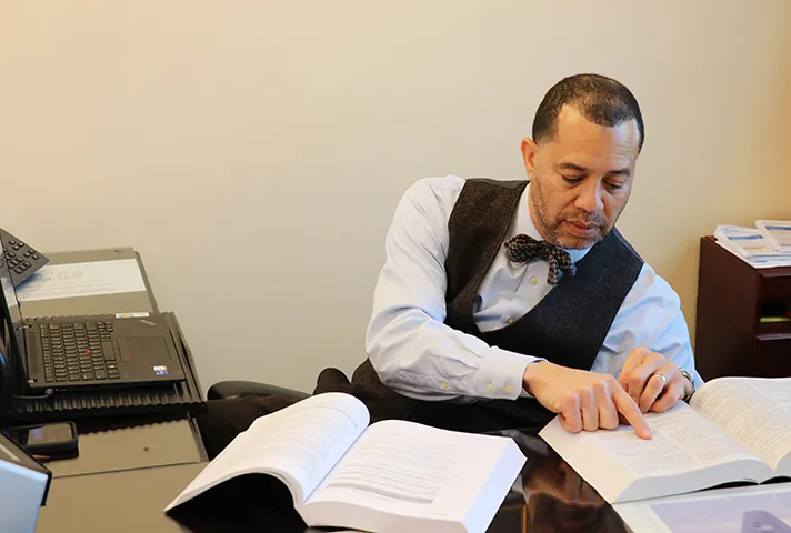 A probation and pretrial services officer sitting at a desk reading and doing research. 